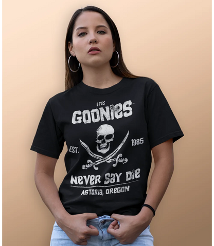 Woman wearing Unisex short sleeve black t-shirt featuring official Warner Bros The Goonies movie poster skull and cross swords design with the iconic text The Goonies, Never Say Die / Retro Tees
