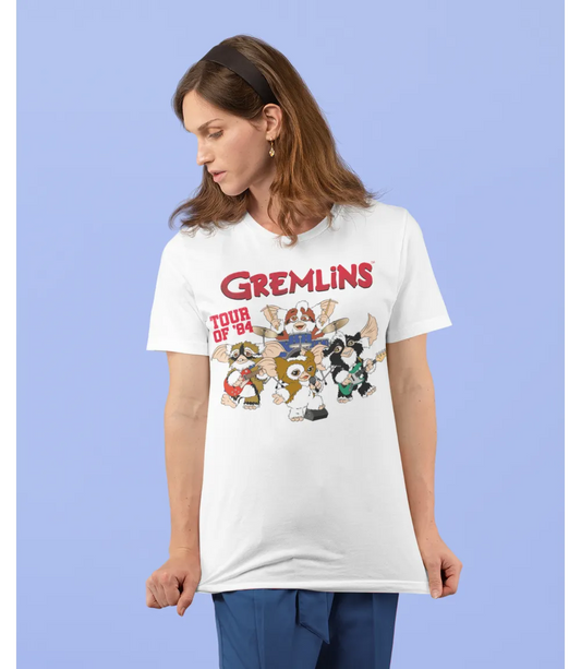 Woman wearing Unisex short sleeve white t-shirt featuring official Warner Bros Gremlins Tour Of 84 - The Mogwais Rock Band design / Retro Tees