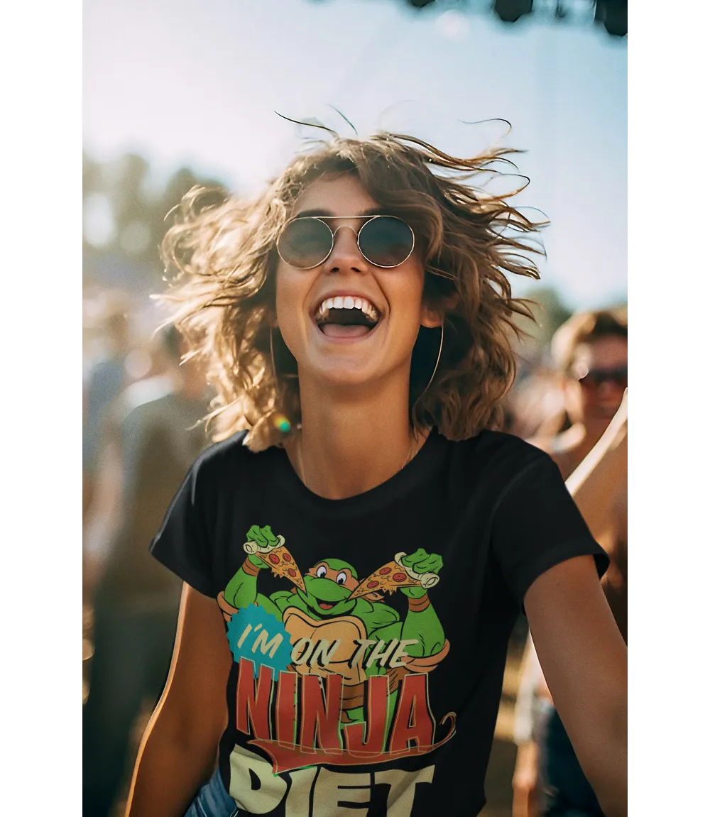 Woman wearing Unisex short sleeve black t-shirt featuring official Teenage Mutant Ninja Turtles Michelangelo with pizza design with I'm on the Ninja Diet text / Retro Tees